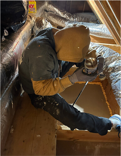 A person sealing air gaps in an attic