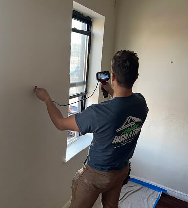 person using borescope to assess home insulation