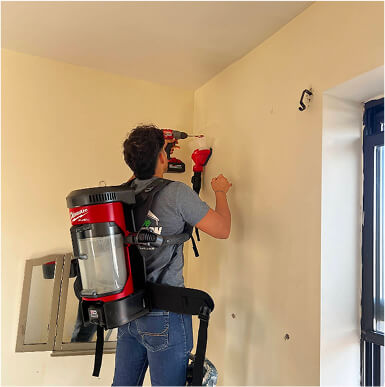 Man with mobile insulation pack on his back injecting foam into a wall
