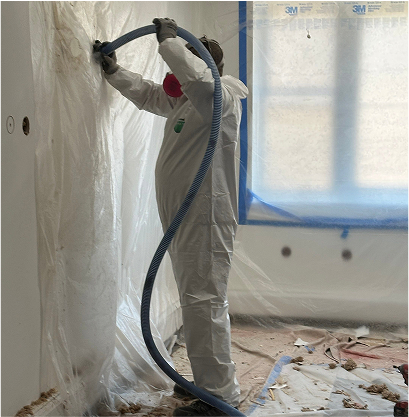 Person covered in protective suit injecting foam in a wall