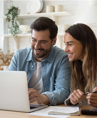 Man and woman couple smiling while working on a laptop