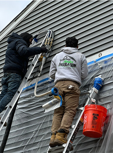 men standing on ladders injecting foam into wall from outside a house