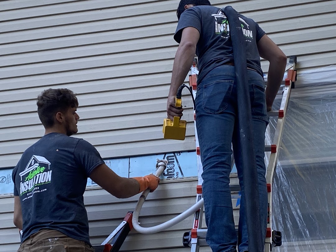 Two workers inject insulation into the side of a wall